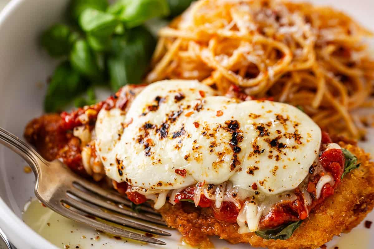 Chicken parmesan after being baked served with pasta.