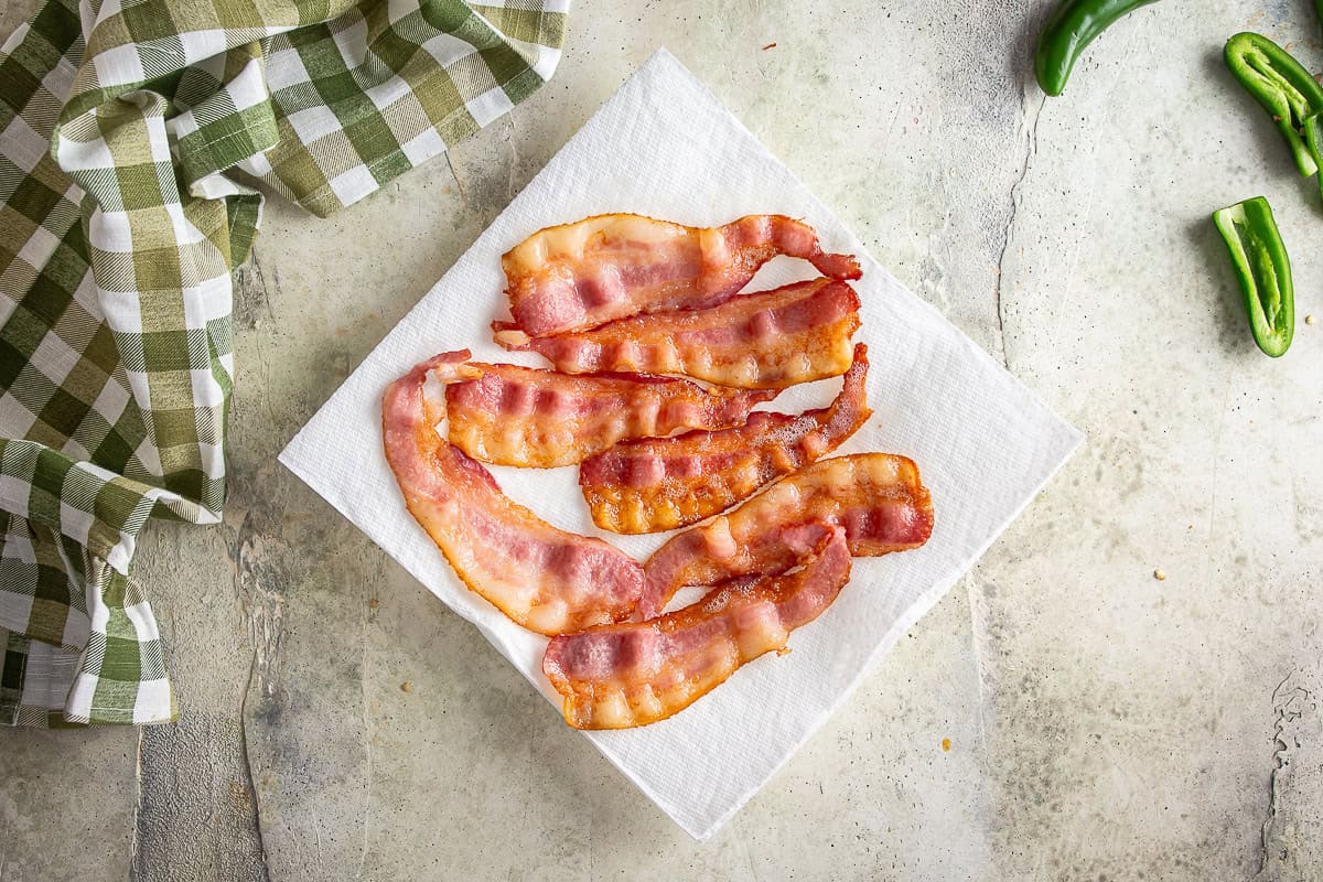 Partially cooked bacon on a paper towel draining.