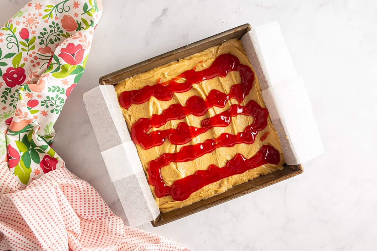 Jam drizzled over blondie batter before being swirled.