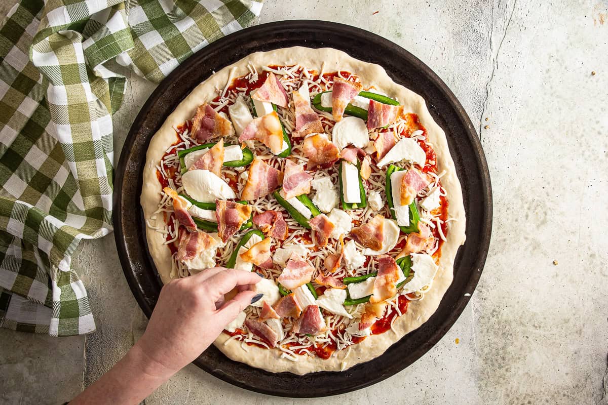 Finishing the topping of the pizza before it hits the oven.