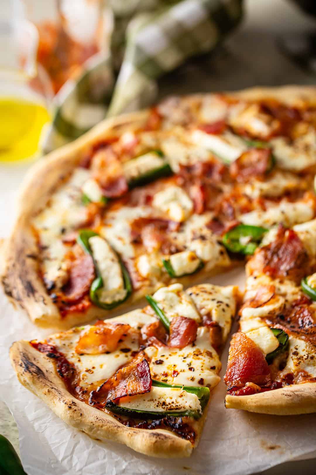 A jalapeno popper pizza with a slice partially removed.