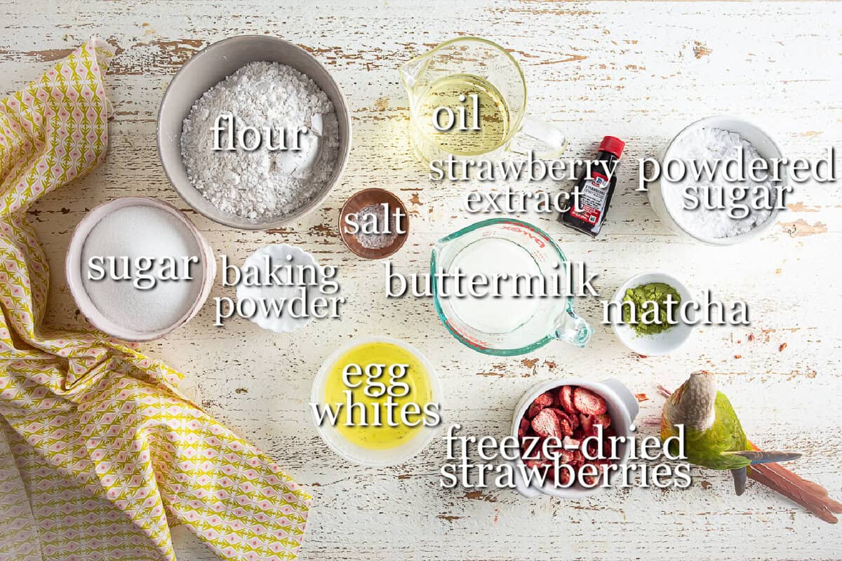Ingredients for a strawberry matcha loaf in separate containers on a wooden background.