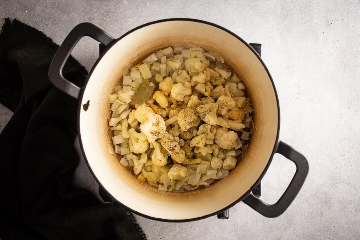 Adding the cauliflower and seasonings to the onions and butter mixture.