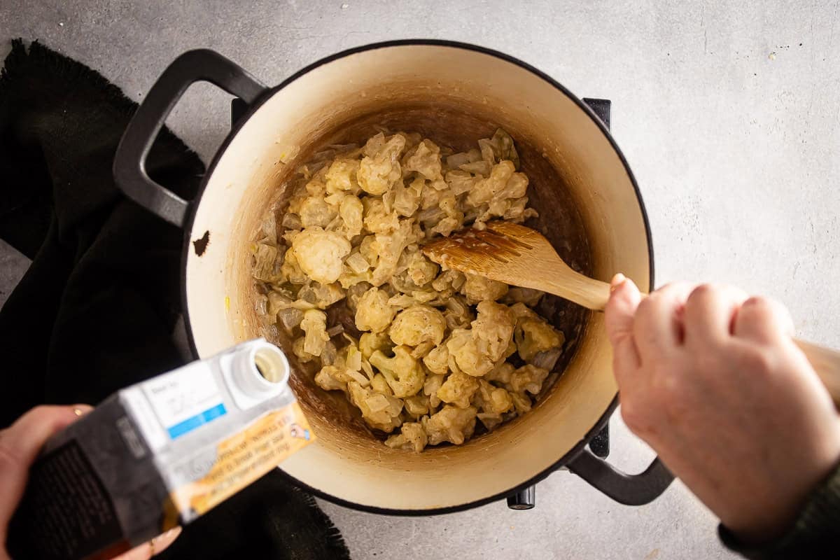 Adding stock to the cauliflower soup.