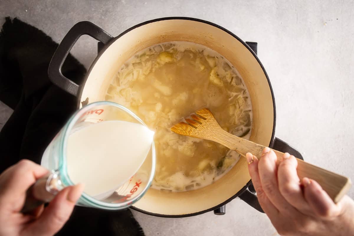 Adding cream to the cauliflower soup mixture.