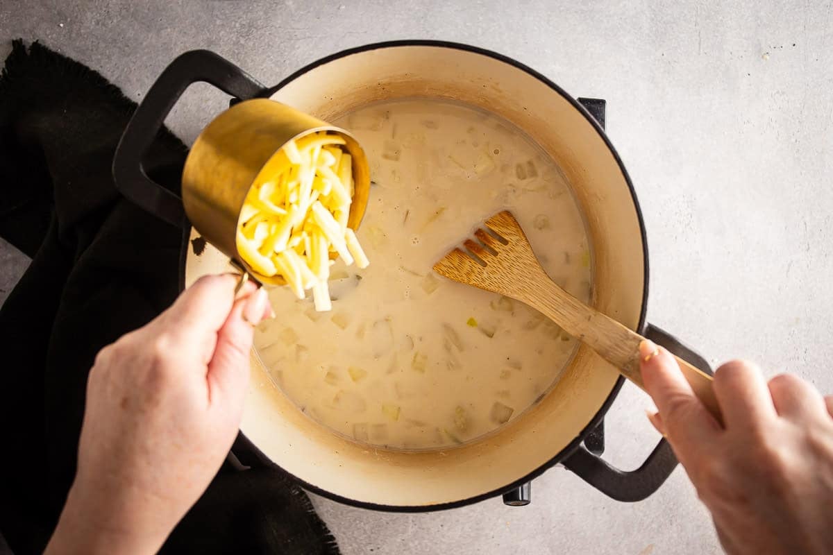 Adding cheese to cauliflower soup after it is off the heat.