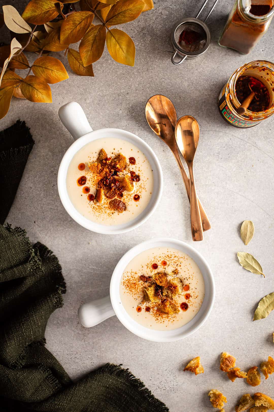 Cauliflower soup bowls with gold spoons.