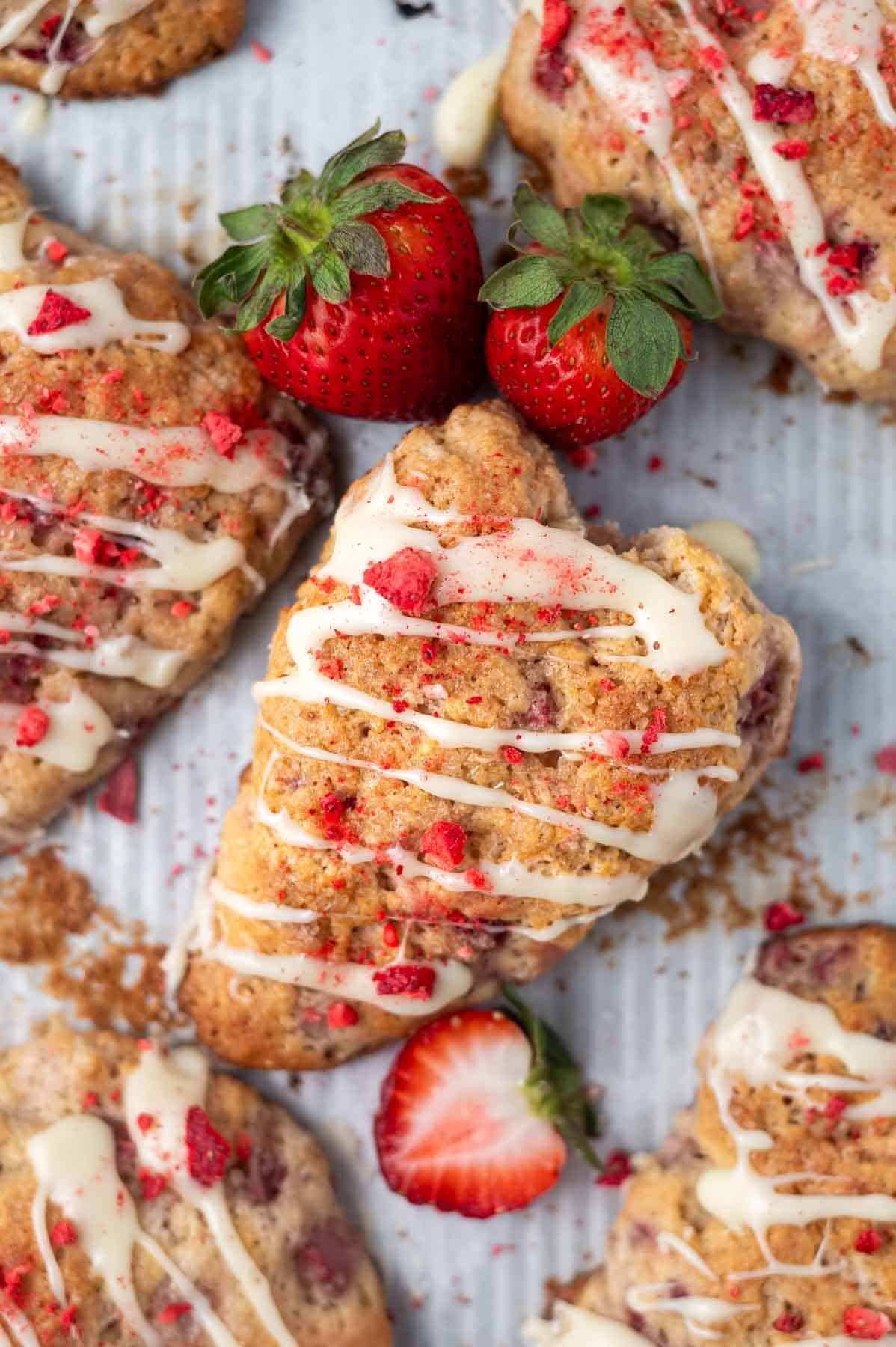 overhead look at strawberry scones on a parchment lined baking pan with fresh strawberries