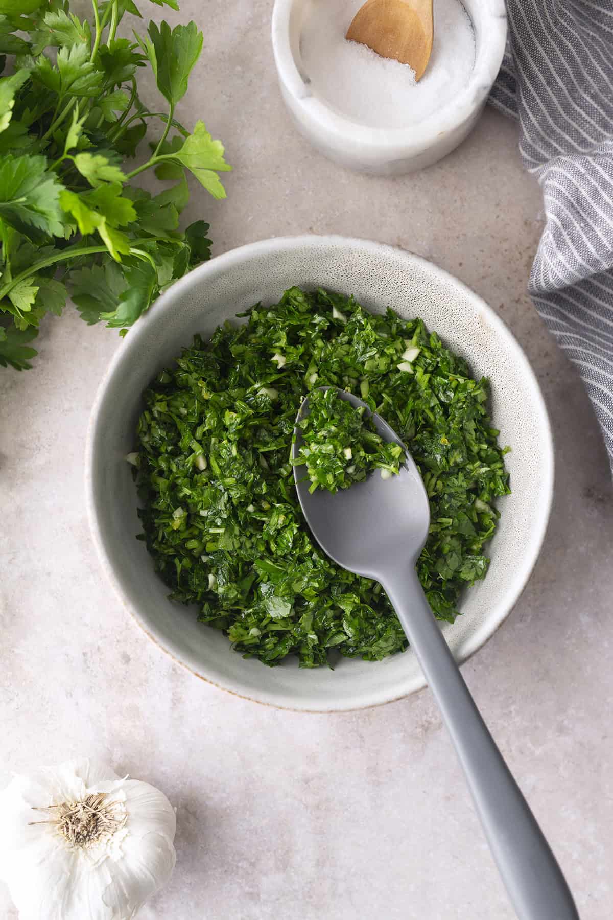Fresh Gremolata on a spoon in a white bowl.