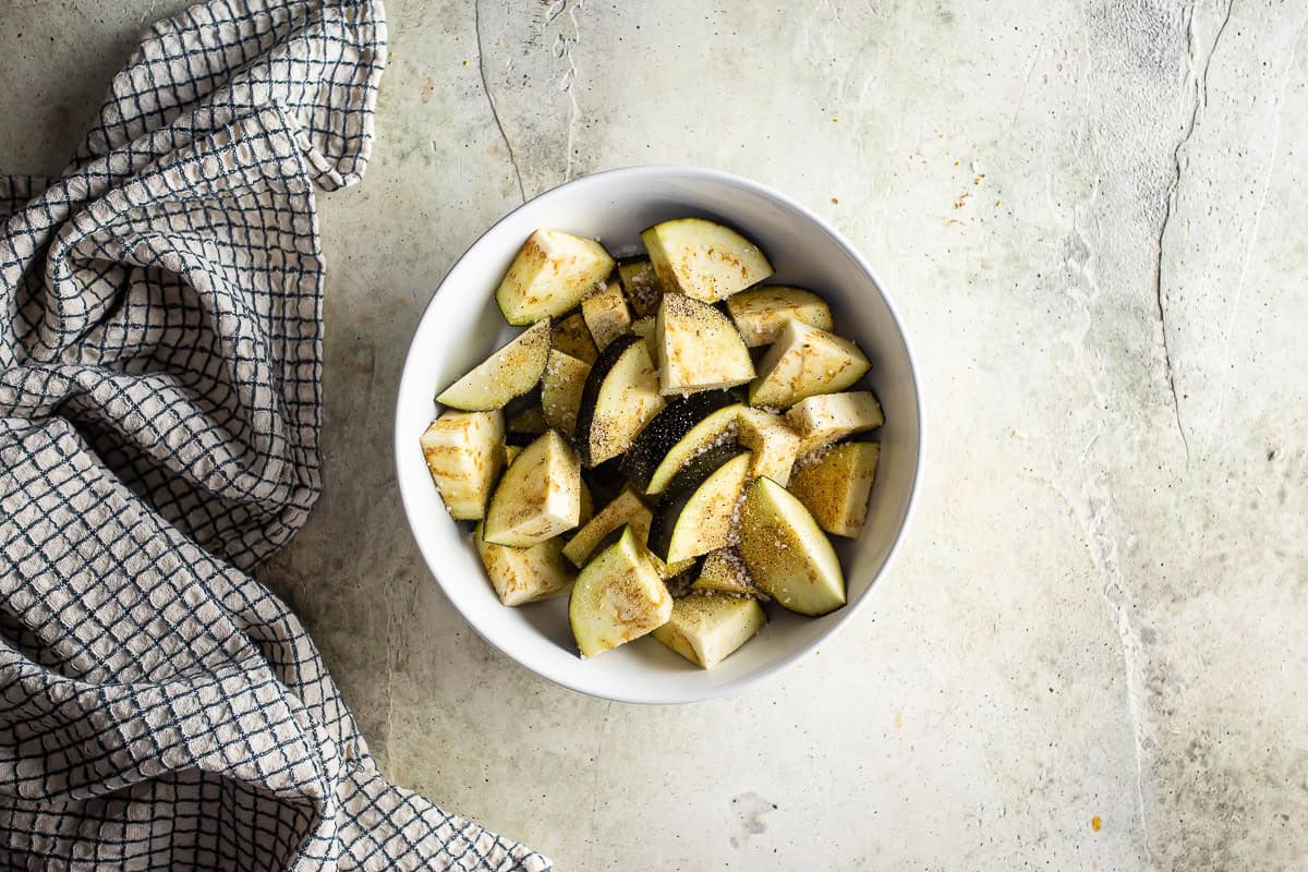 Seasoned cut eggplant in a white bowl.