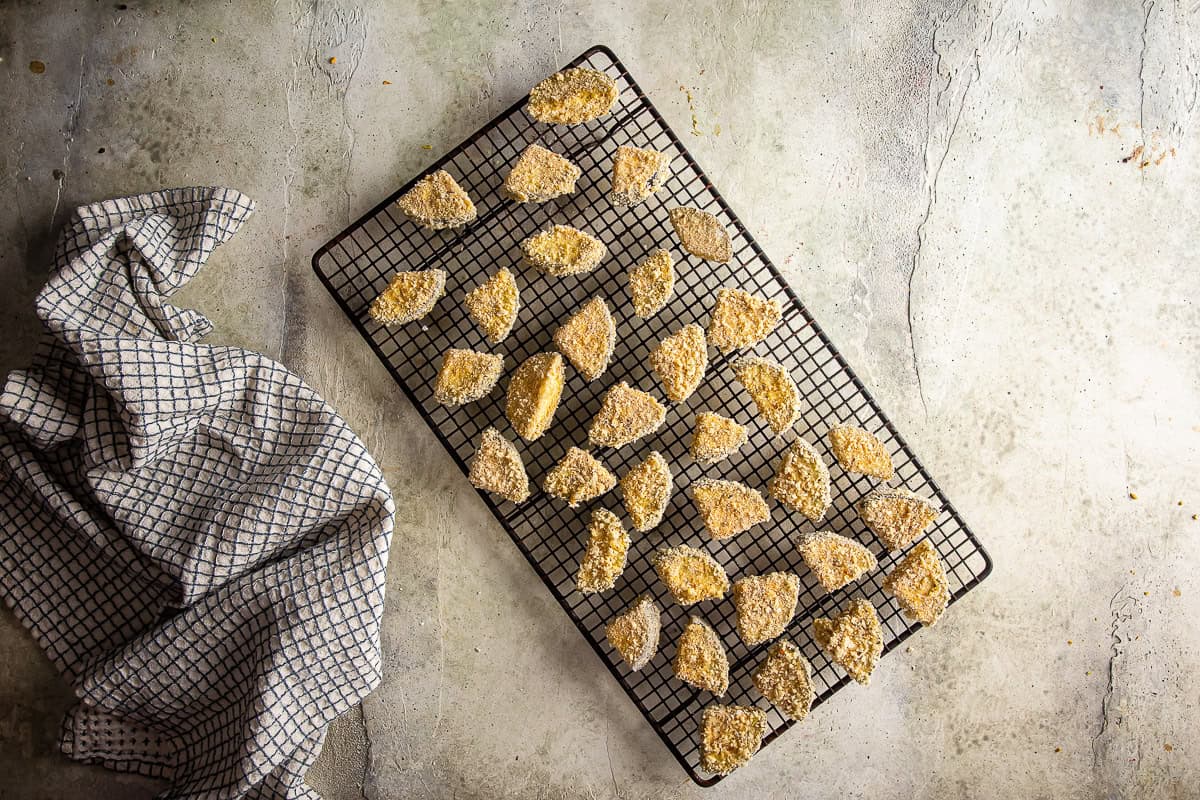 Breaded eggplant on a wire rack before being fried for eggplant parmesan pizza.