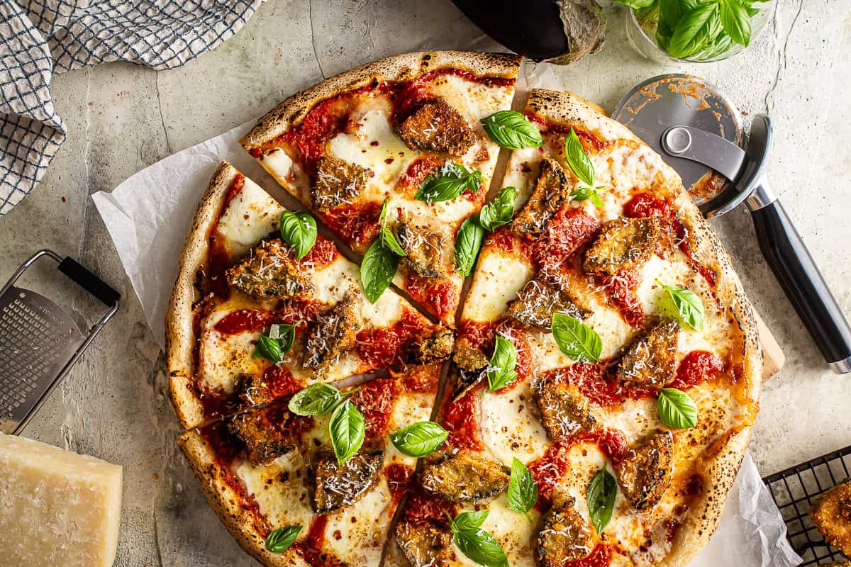 Baked eggplant parmesan pizza with fresh basil on top.