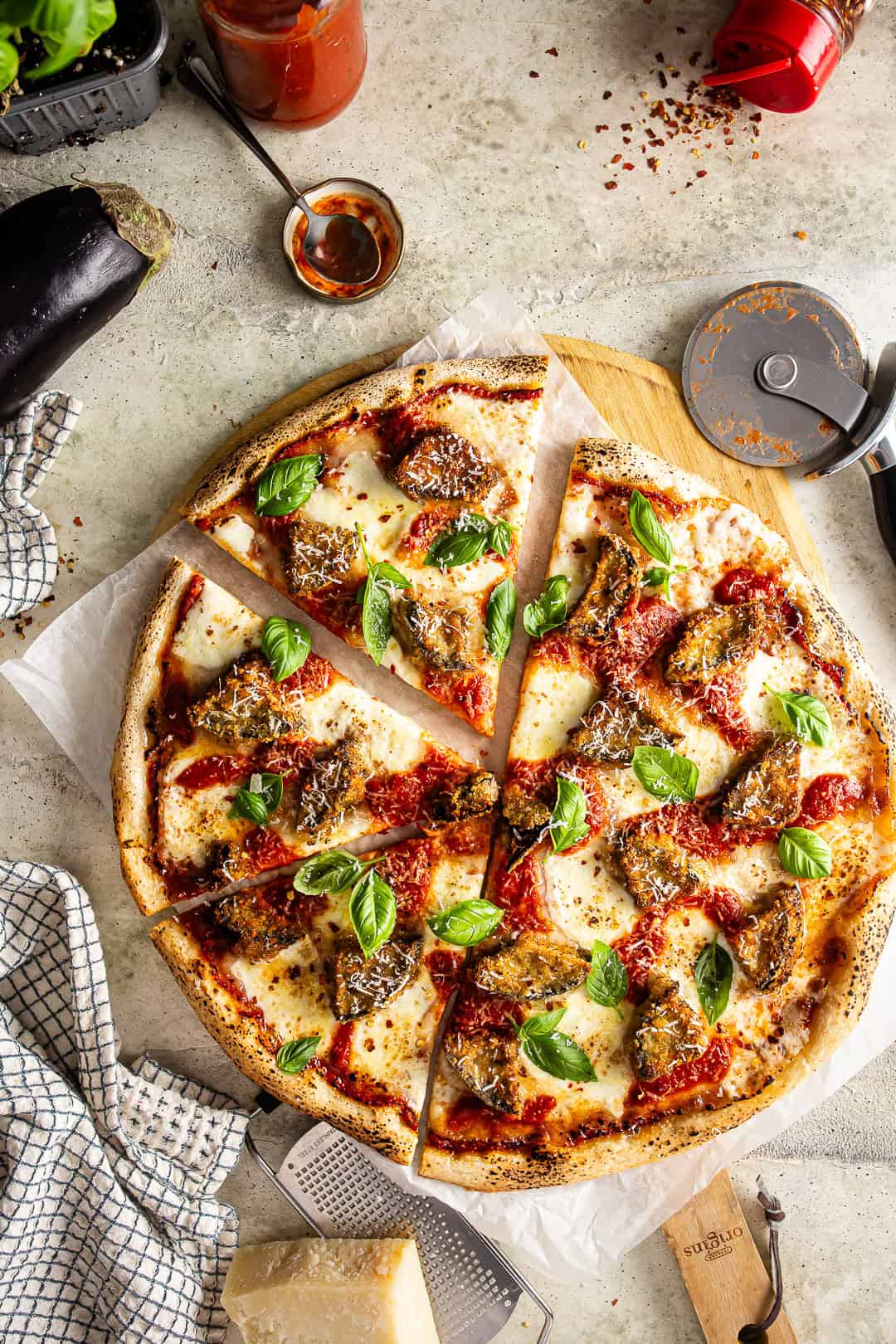 Eggplant Parmesan Pizza with a slice cut out and a pizza cutter near the pizza.