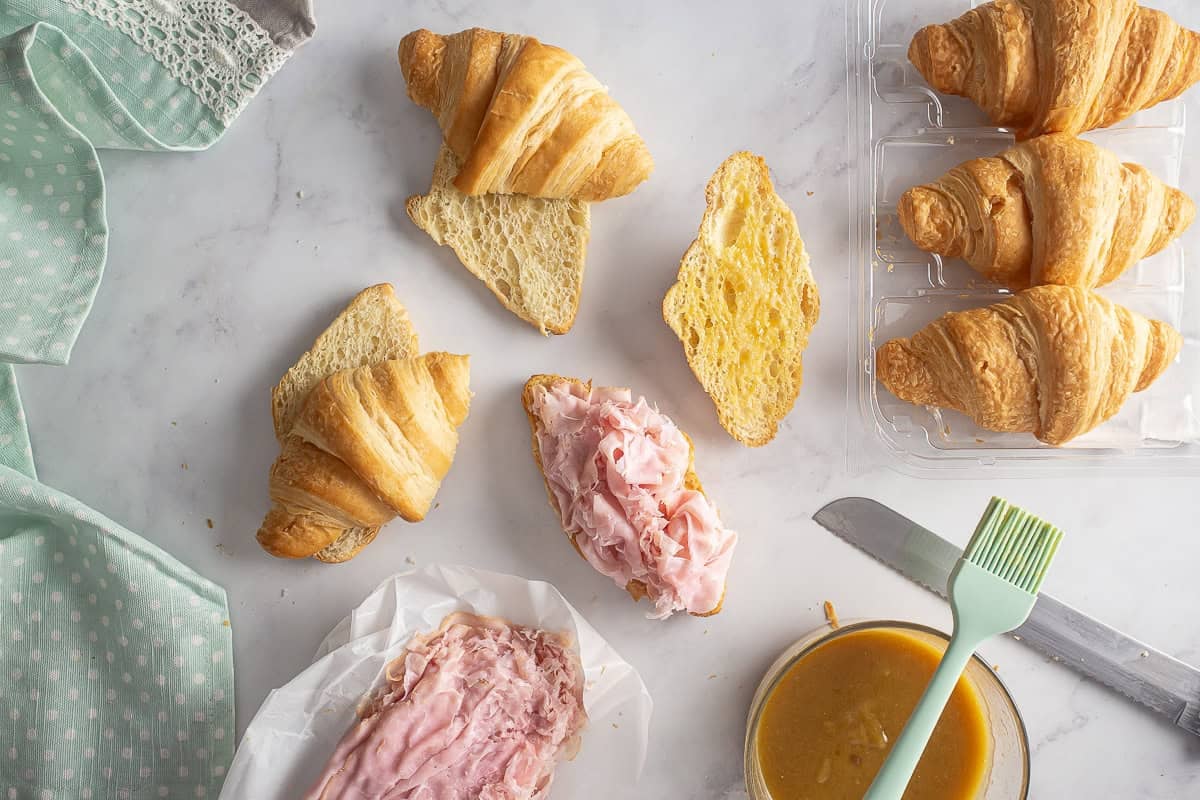Sliced croissants with ham layered on top.