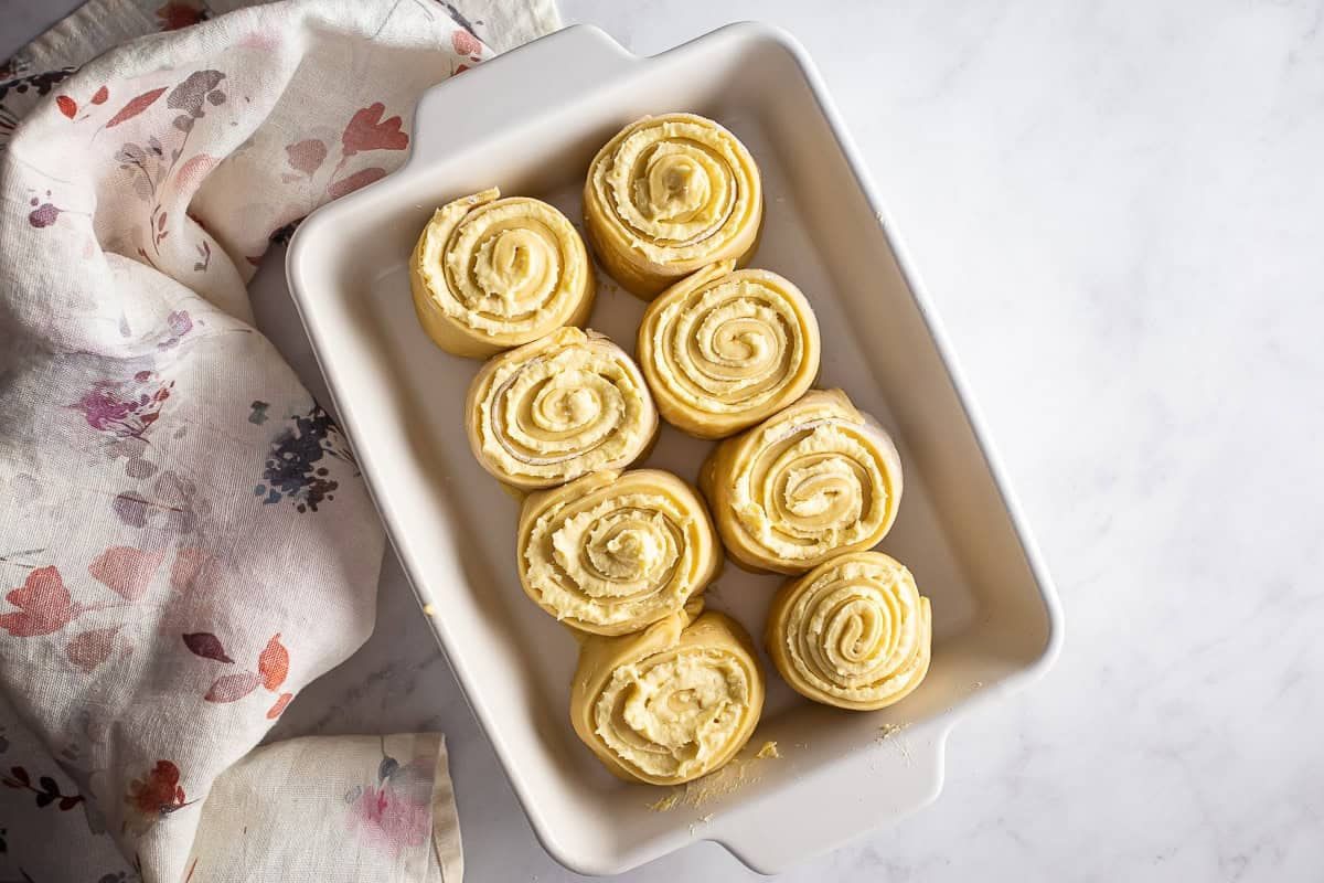 Almond rolls placed into a baking dish before being covered and before they rise.