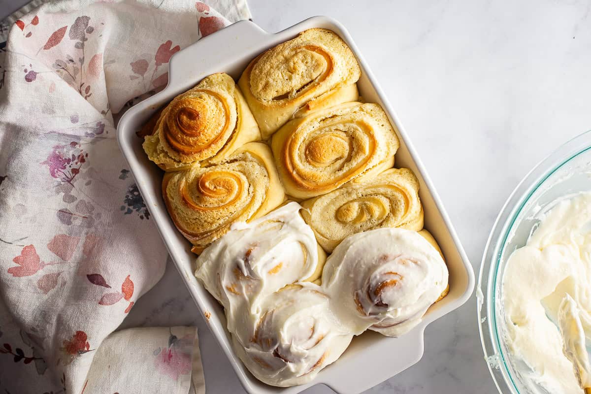 Spreading almond roll icing onto the warm almond rolls.
