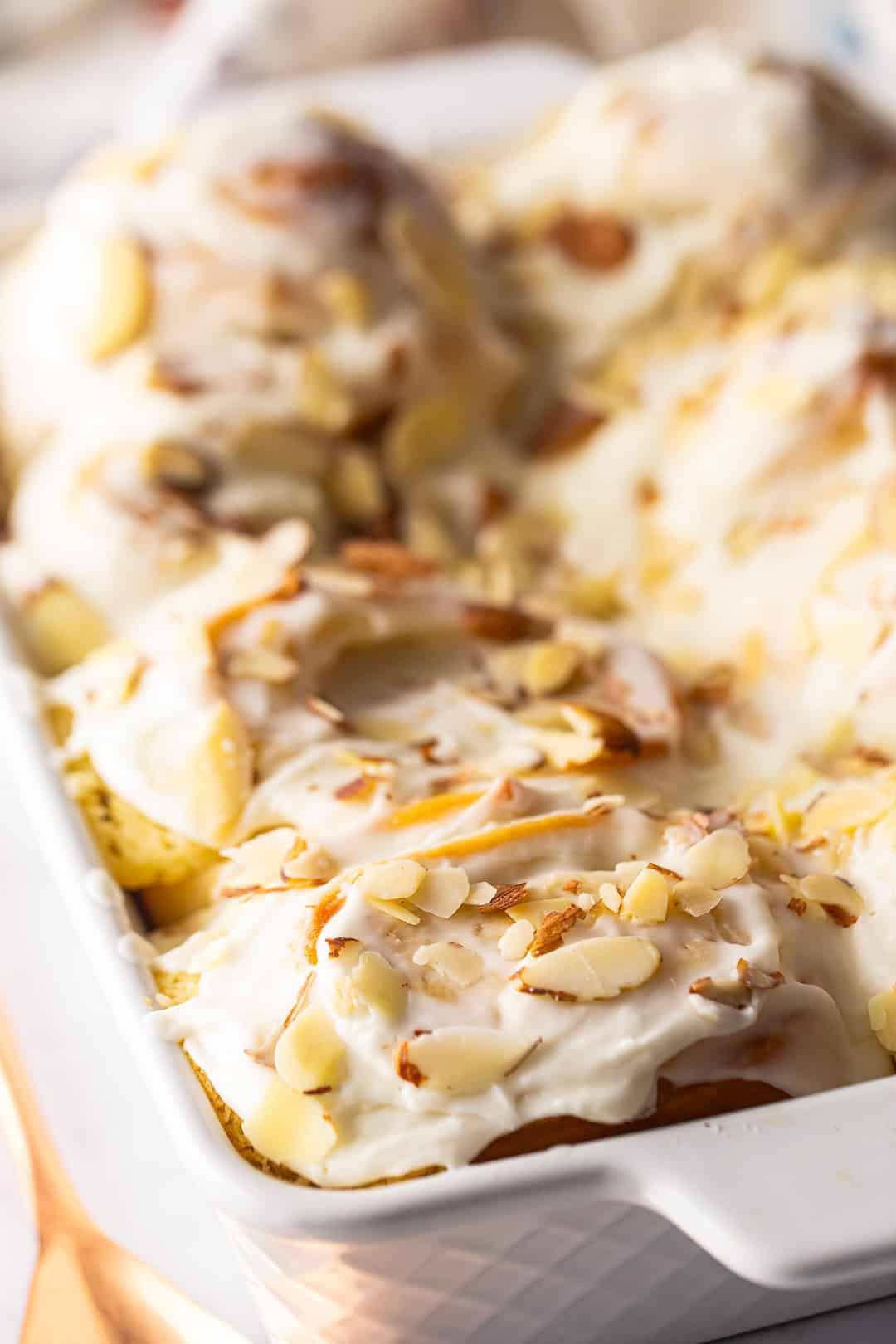 Almond rolls in a white pan with slivered almonds on top.