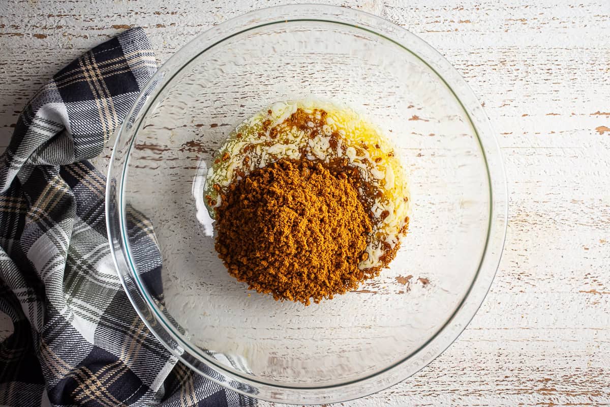 Biscoff cookie crumbs and melted butter in a large glass bowl before being mixed.