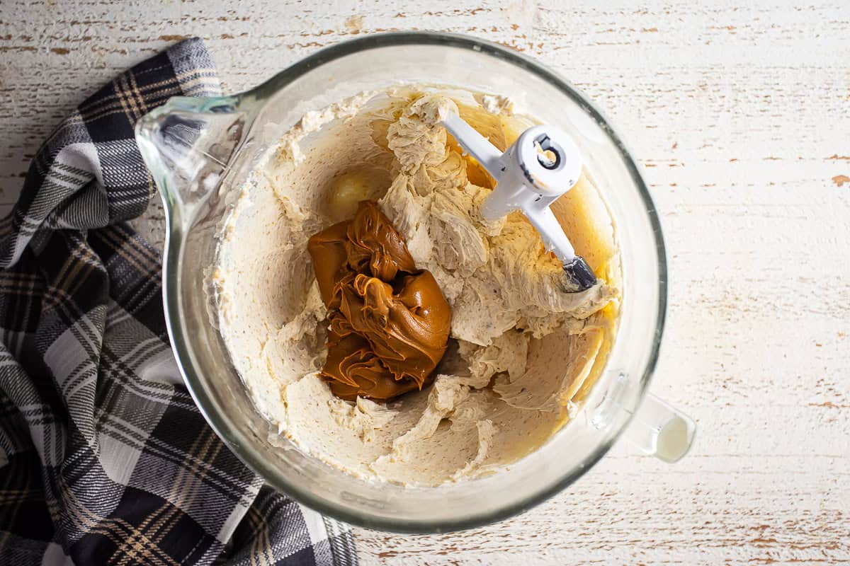 Cookie butter being added to the cream cheese and sugar mixture.