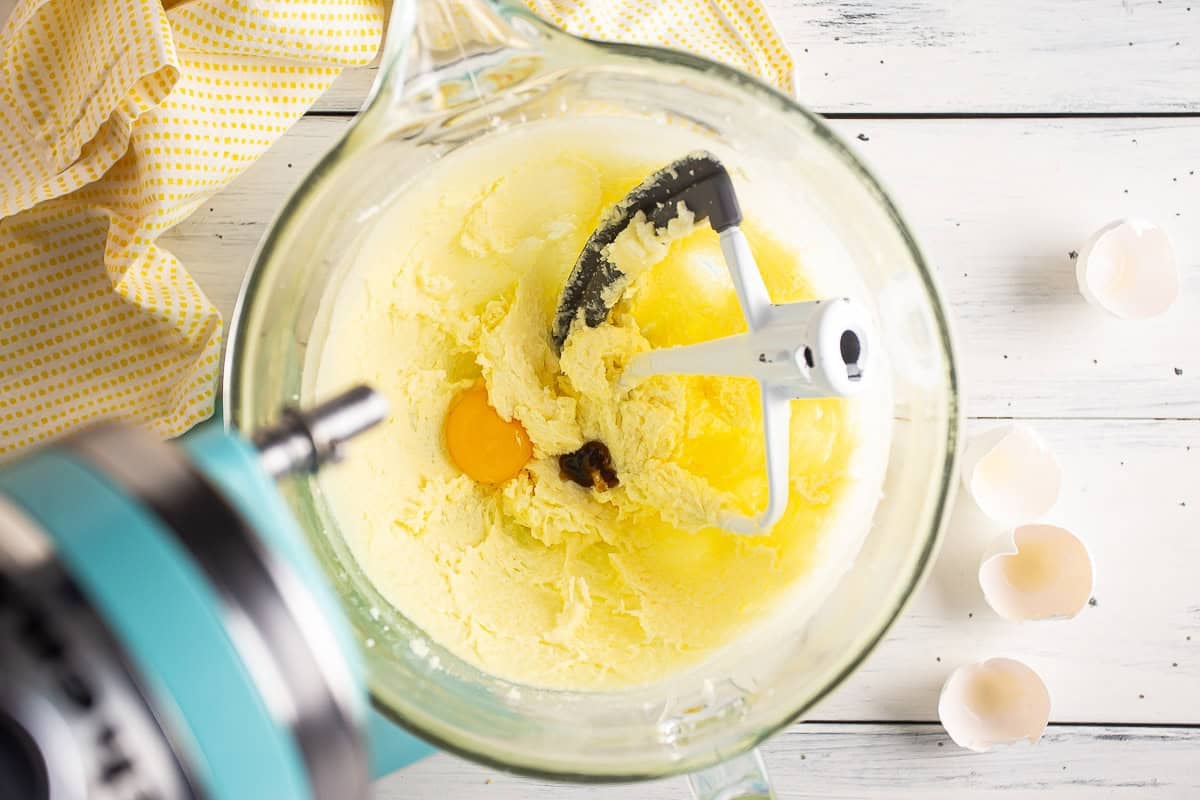 Adding egg yolk and vanilla to cookie dough.