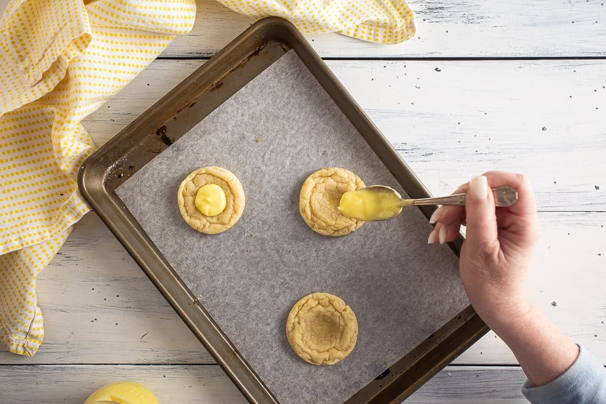Adding lemon curd to the shaped cookies.