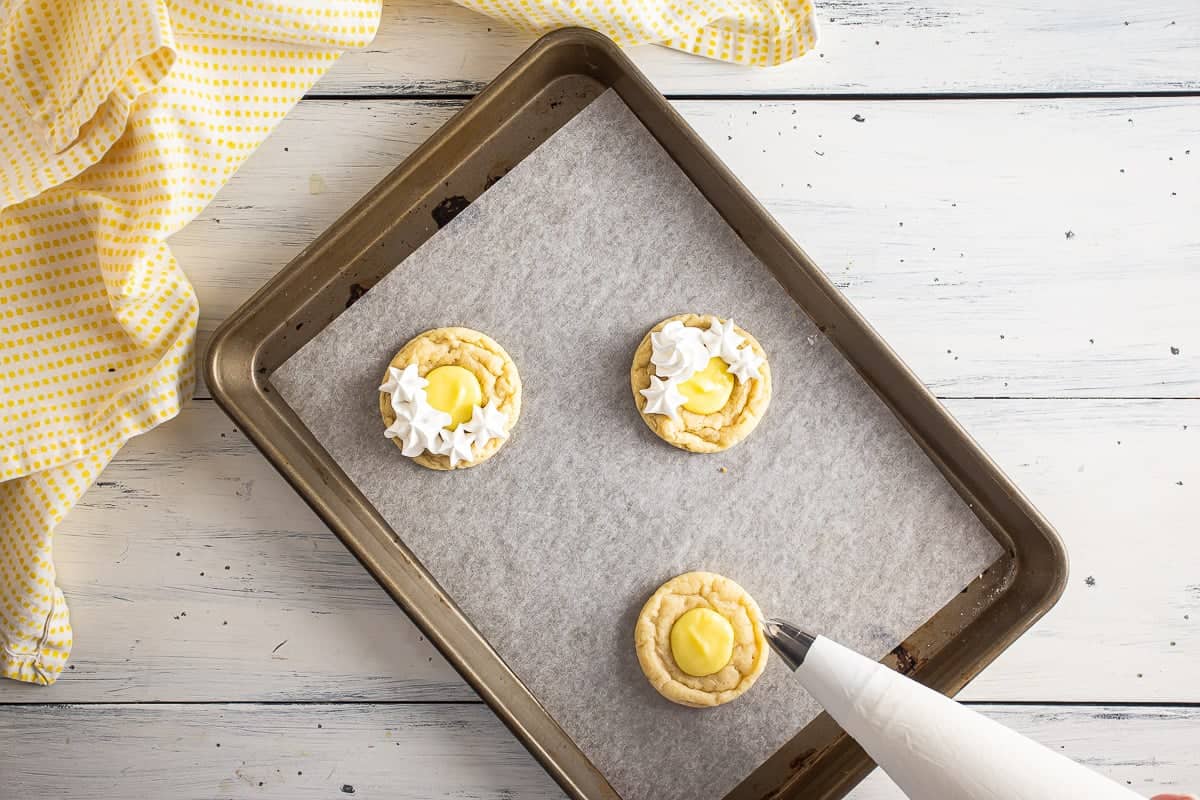 Piping meringue onto the cookies.