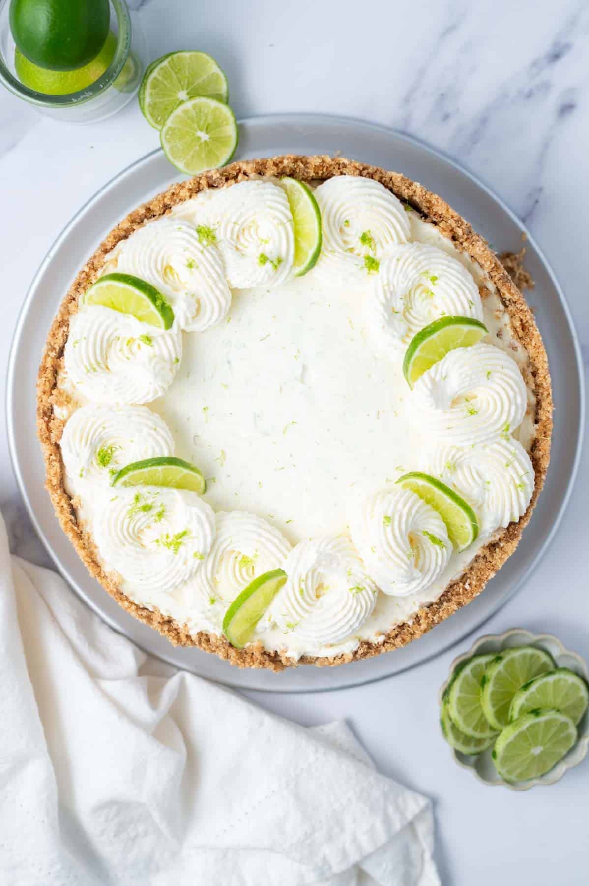 overhead look at key lime cheesecake with whipped cream swirls and lime slices