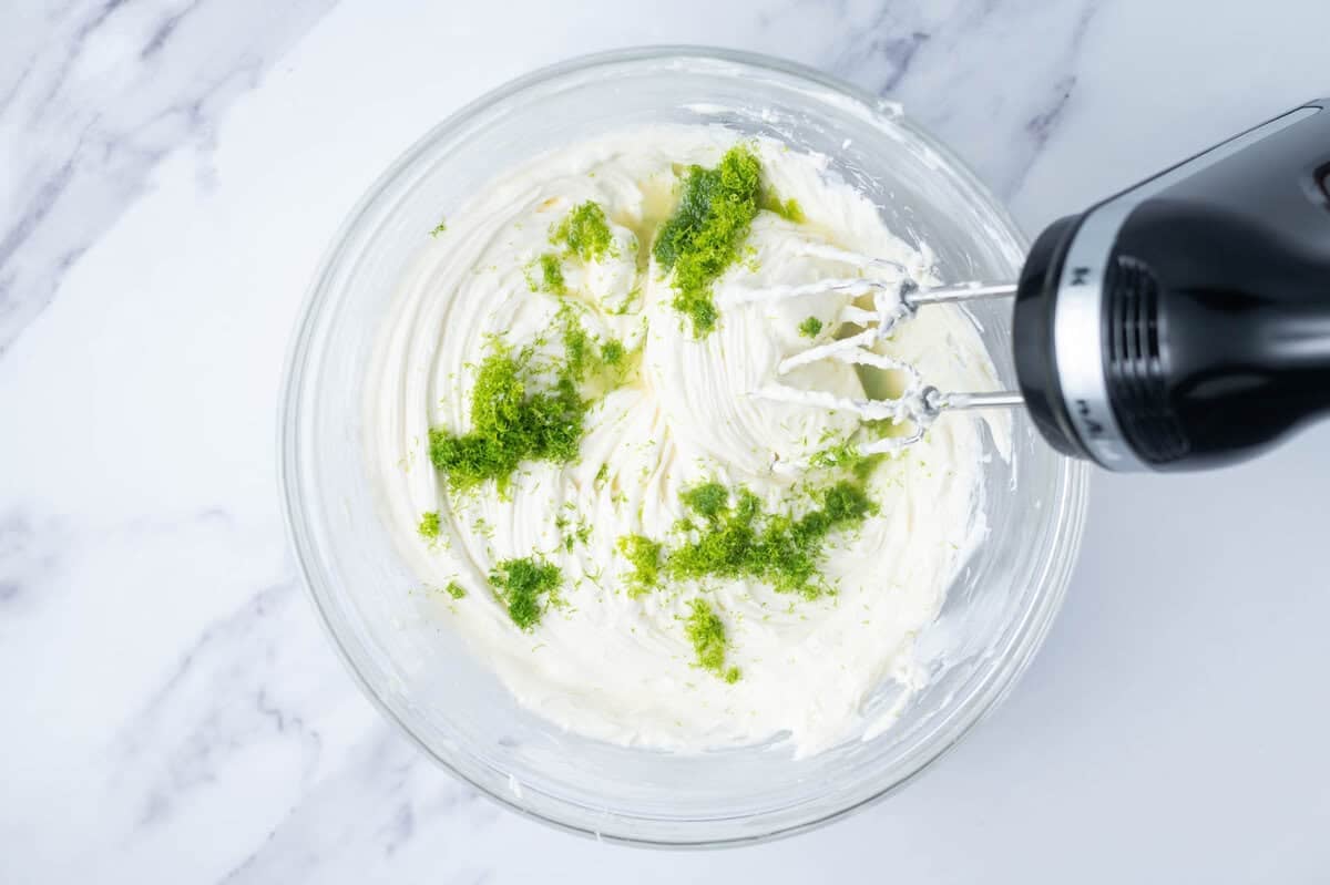 lime zest added to cheesecake filling in a bowl