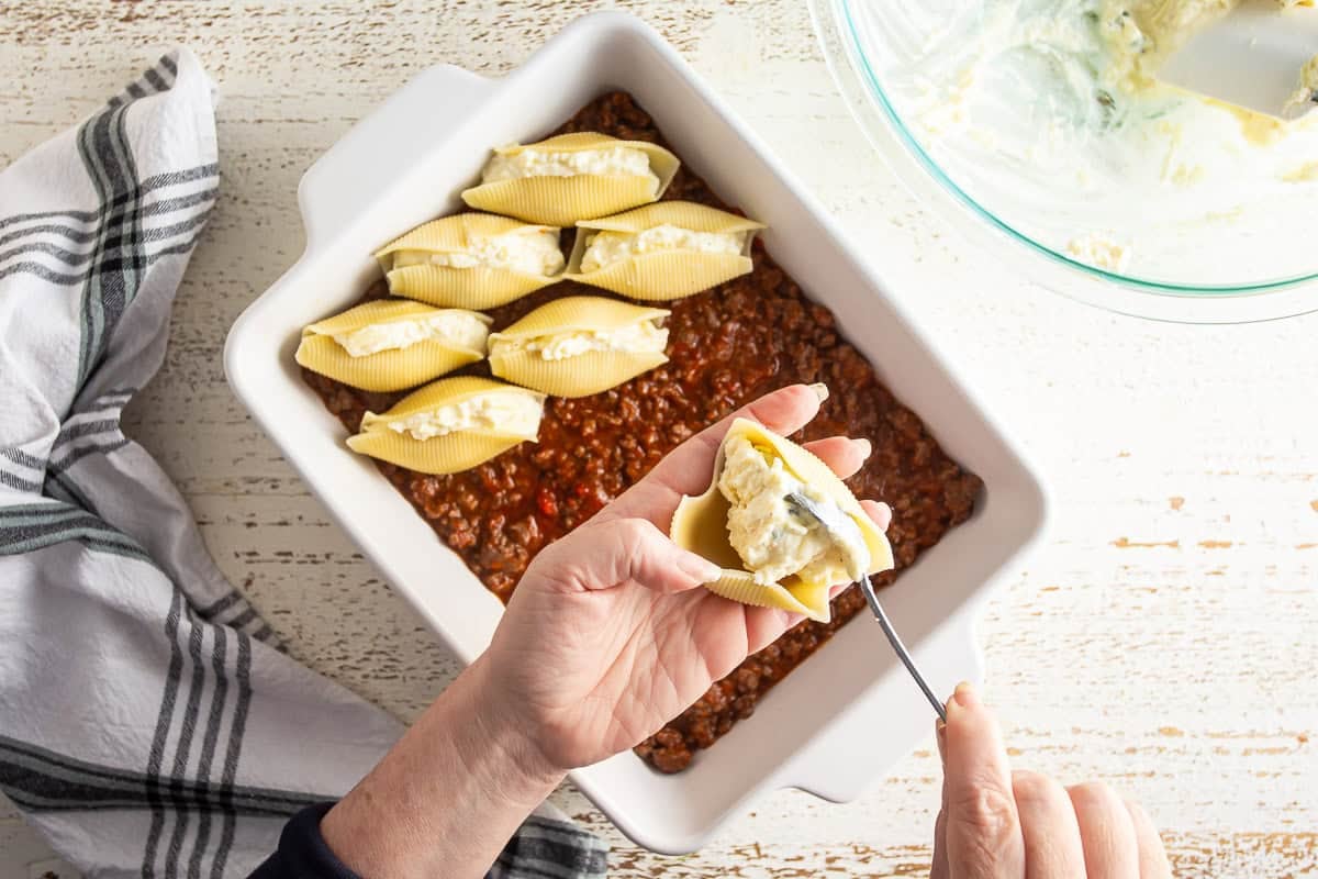 Filling the pasta with cheese mixture and placing it into a baking dish