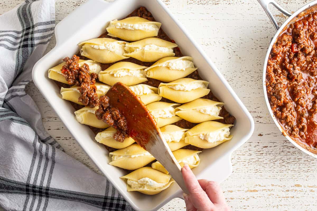 Topping the filled shells with some of the meat sauce