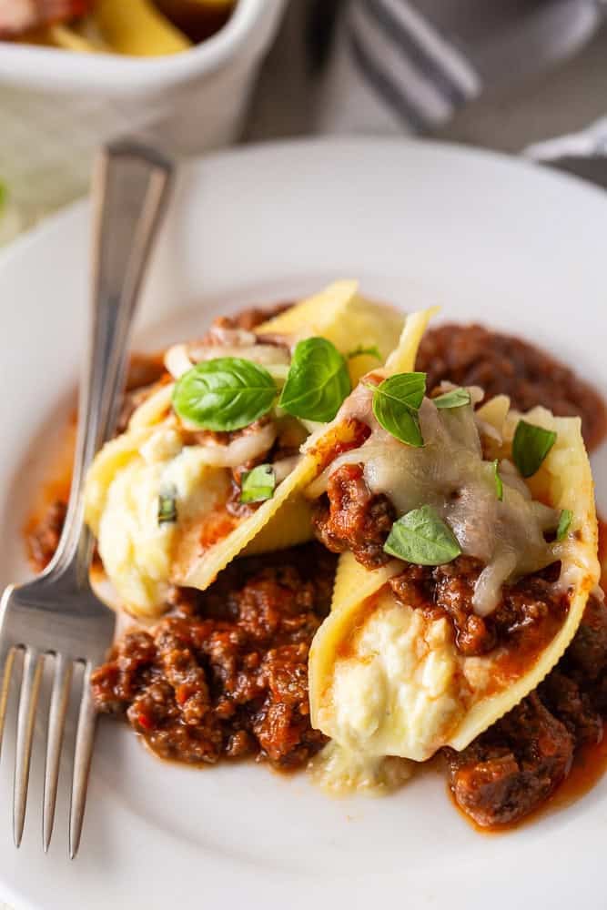 Stuffed shells on a plate with meat sauce and a fork