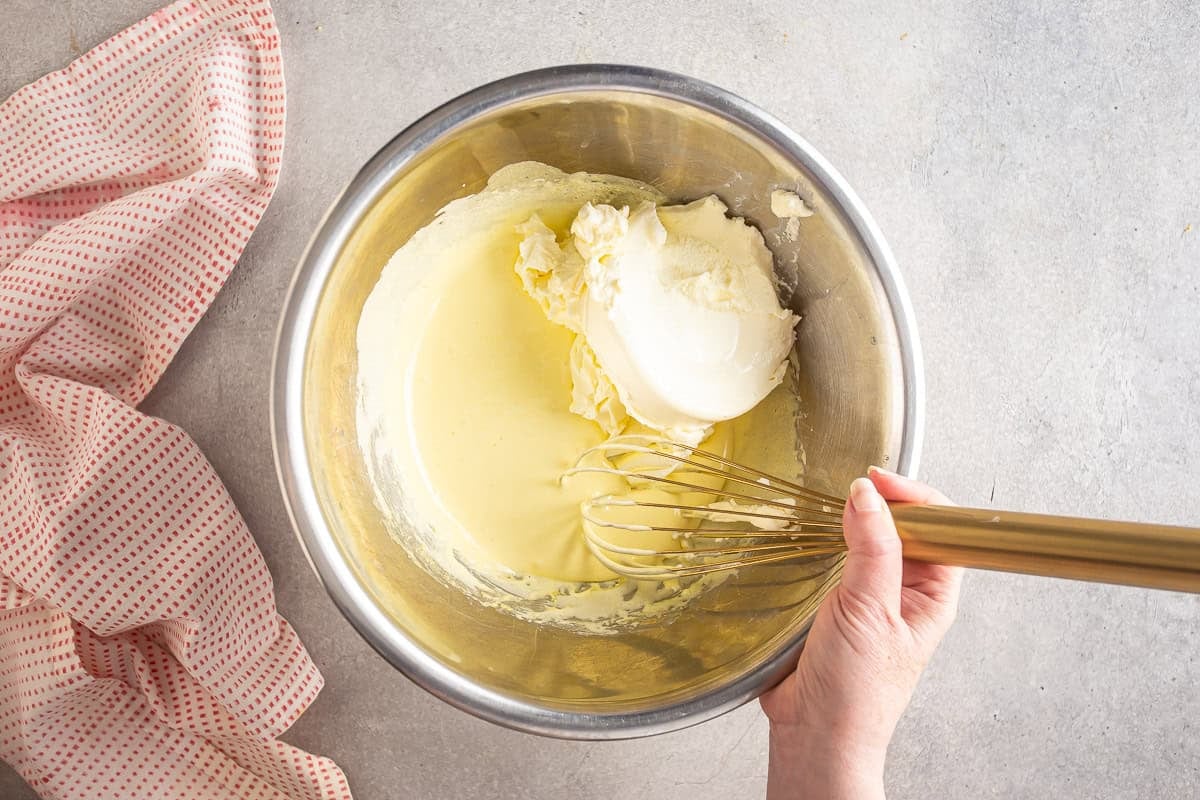 Adding mascarpone to the whipped egg yolks and sugar mixture.