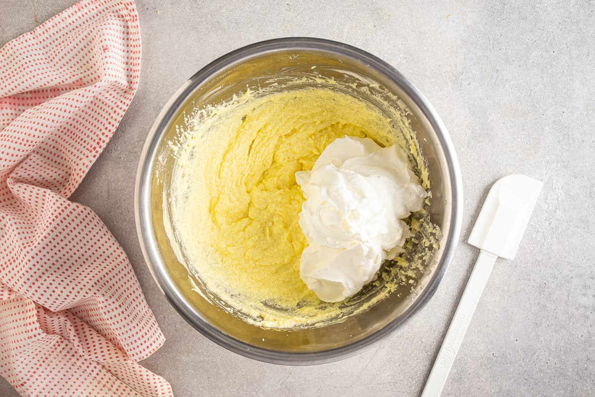Adding whipped cream to the mascarpone mixture for strawberry tiramisu.