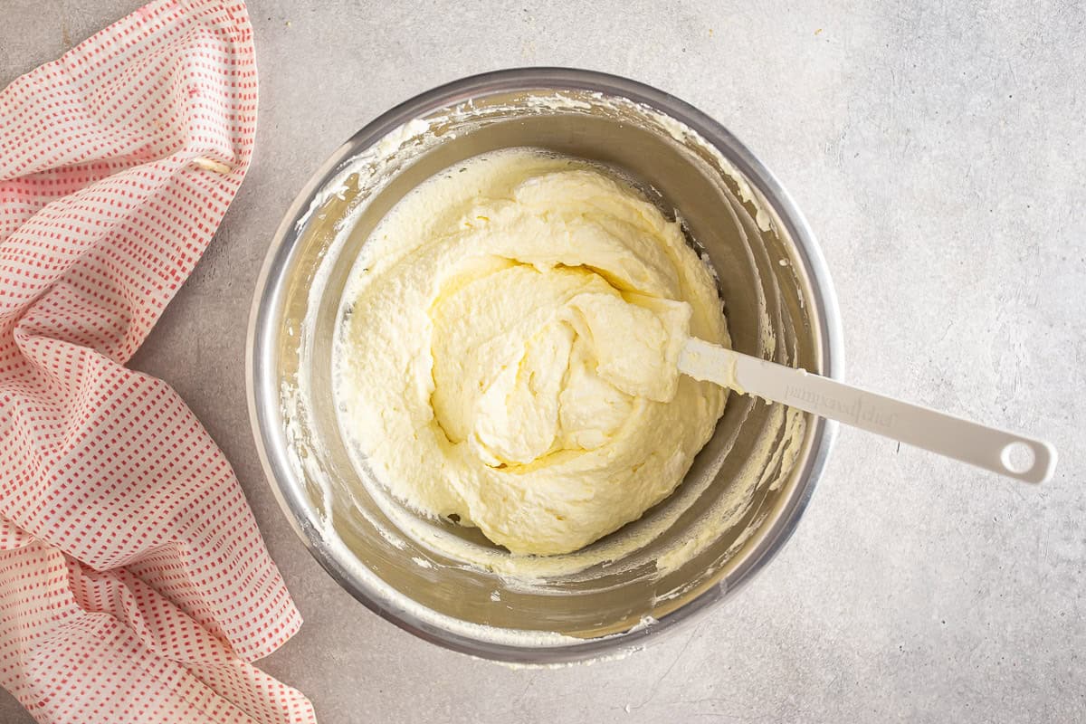 Folding whipped cream into the mascarpone filling mixture.