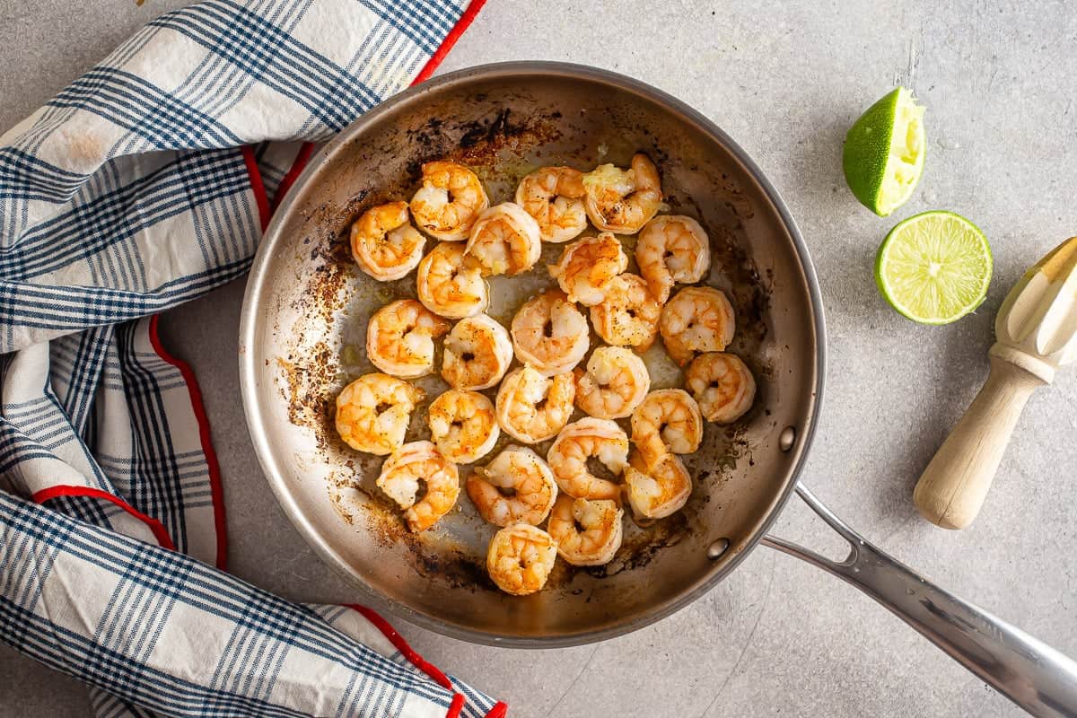Adding lime juice to cooked shrimp for tacos.