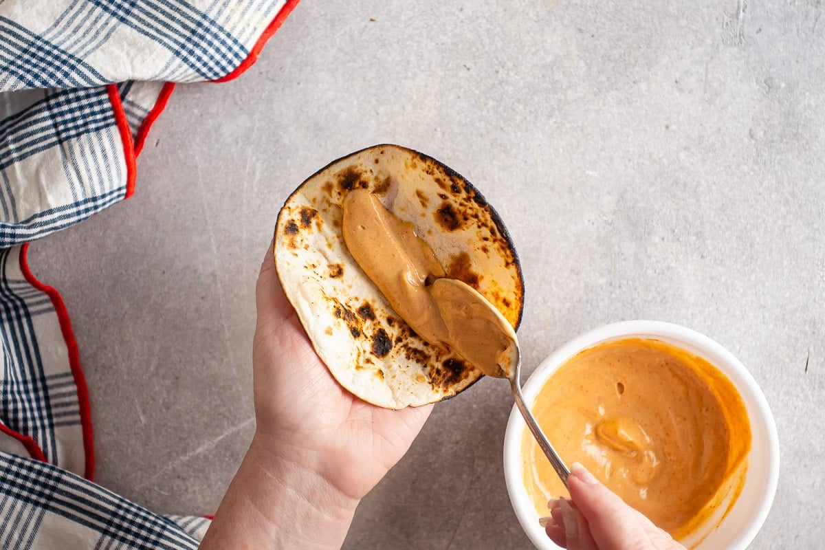 Adding sriracha mayo to warmed tortillas.