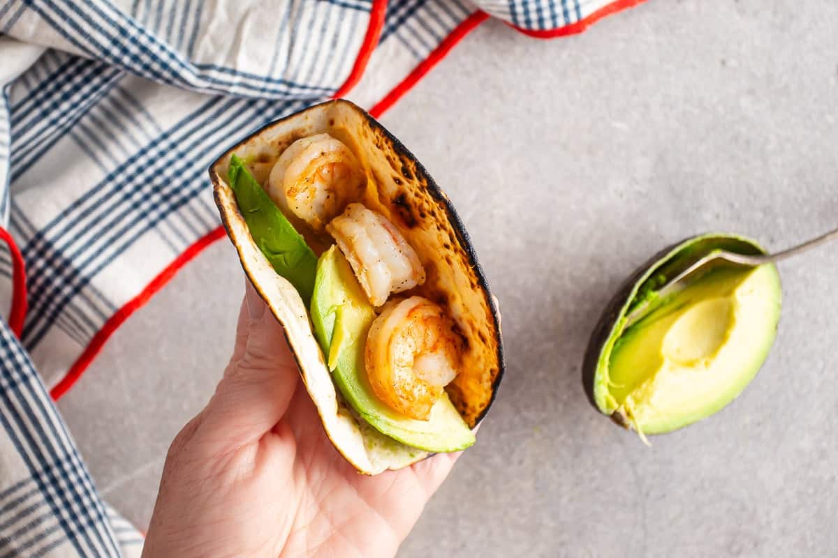 Layering the shrimp and avocado into the tacos.