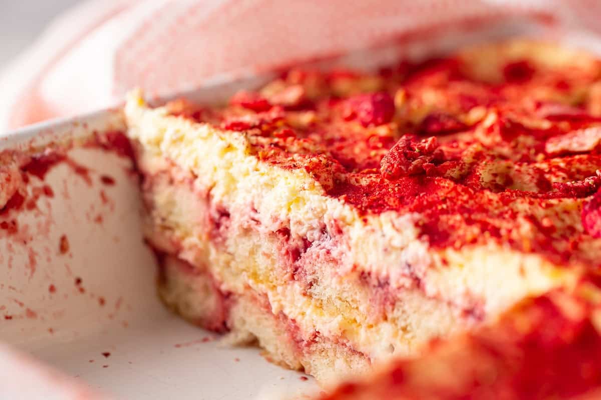 A pan of strawberry tiramisu with a slice taken out.