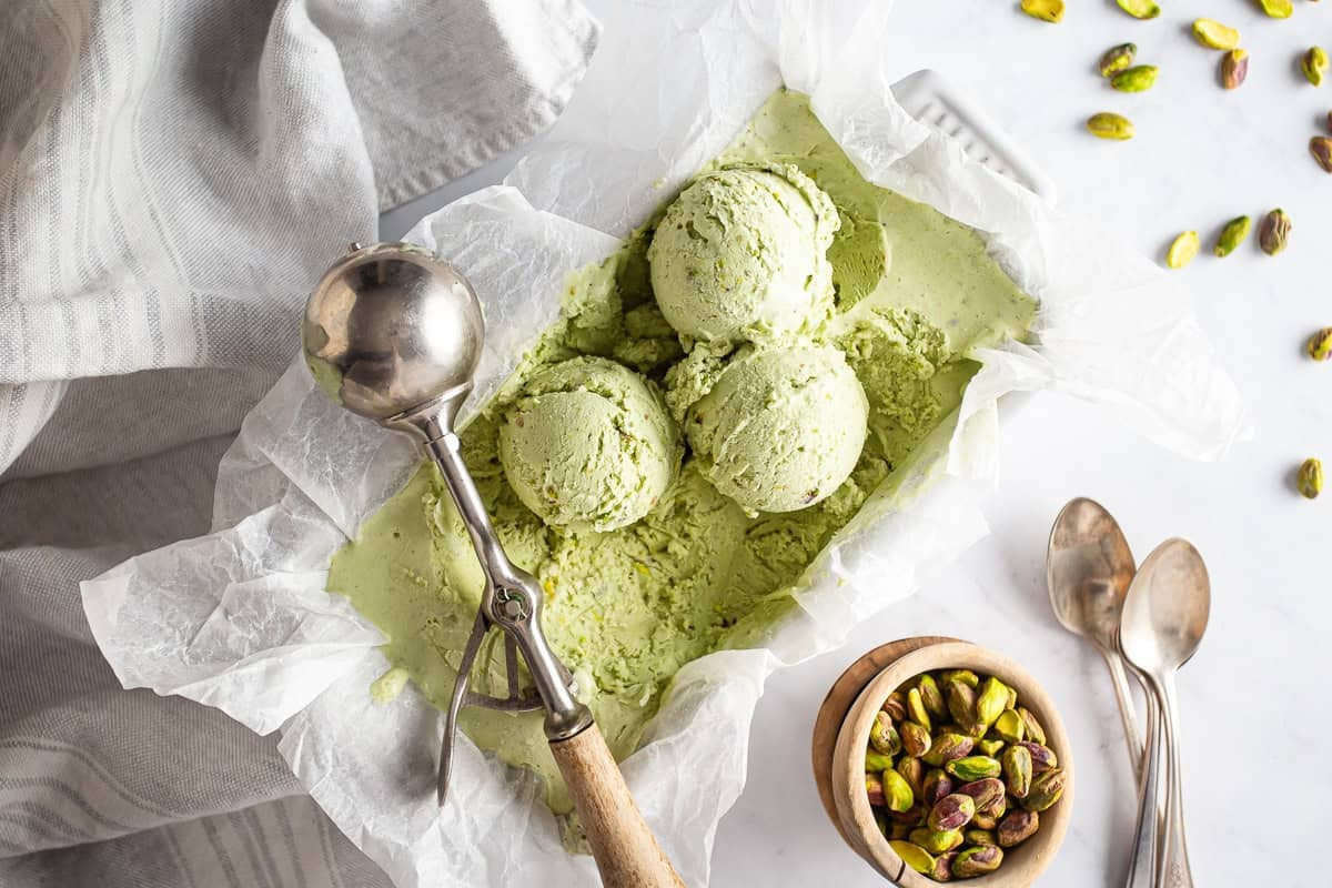 Pistachio ice cream in a container with an ice cream scoop