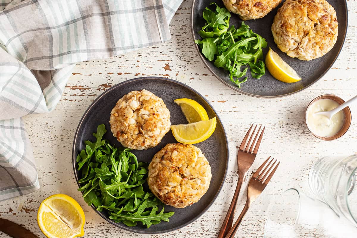 homemade crab cakes on a plate with lemon and lettuce