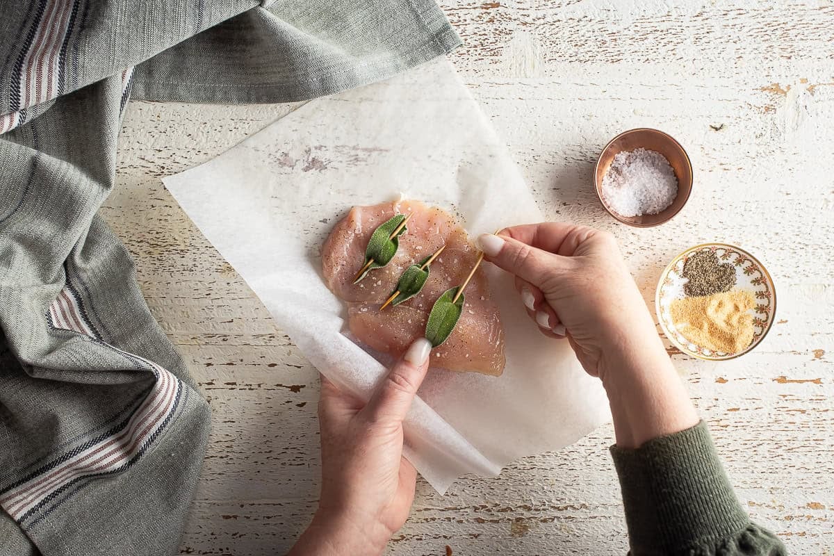 Seasoned chicken breast with sage on top.
