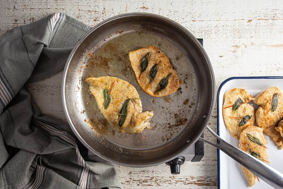 Cooking chicken breast in a stainless steel skillet.