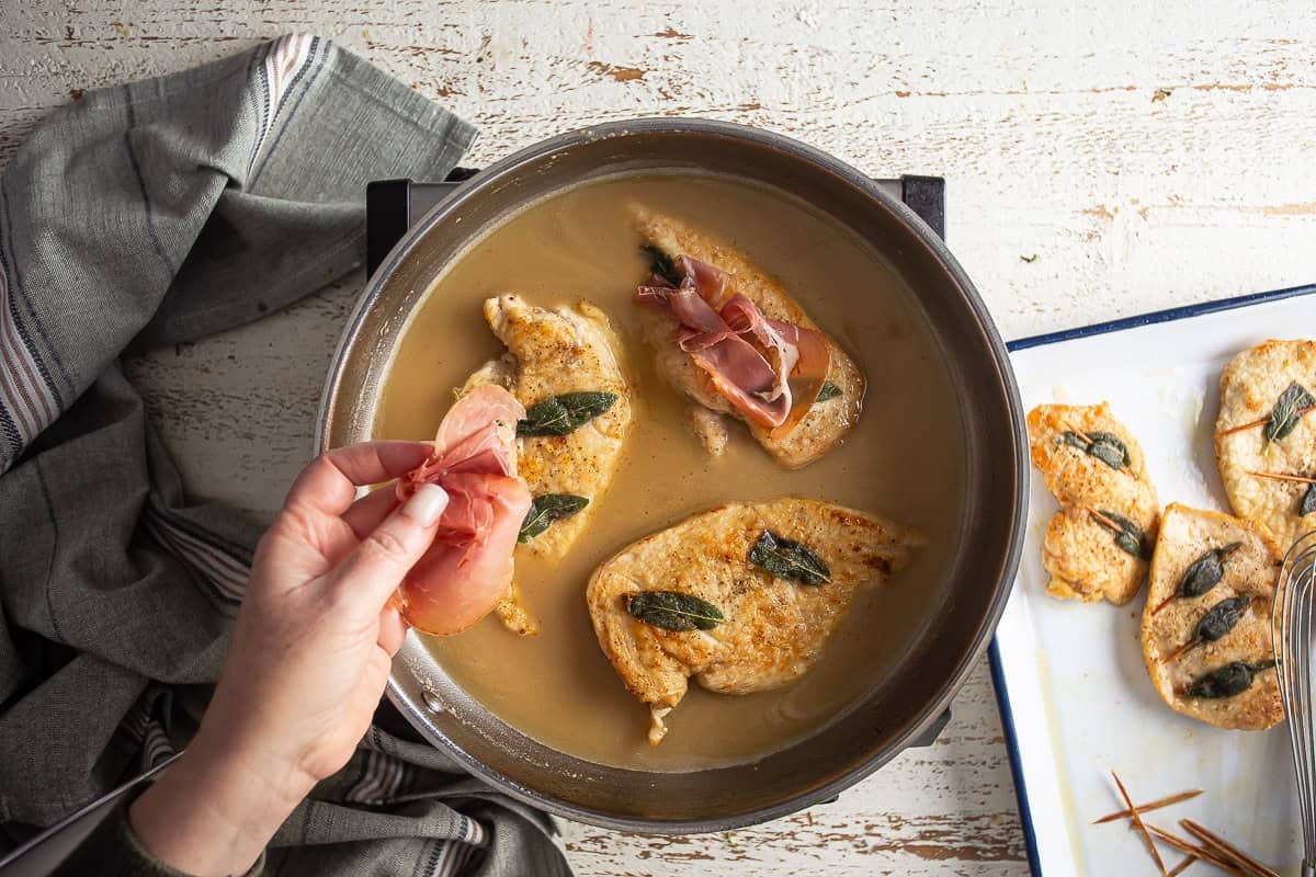 Adding prosciutto to the chicken breasts in the sauce.