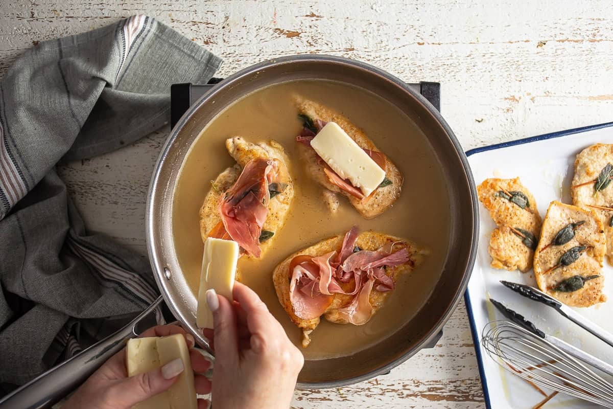 Adding fontina cheese to the chicken saltimbocca.