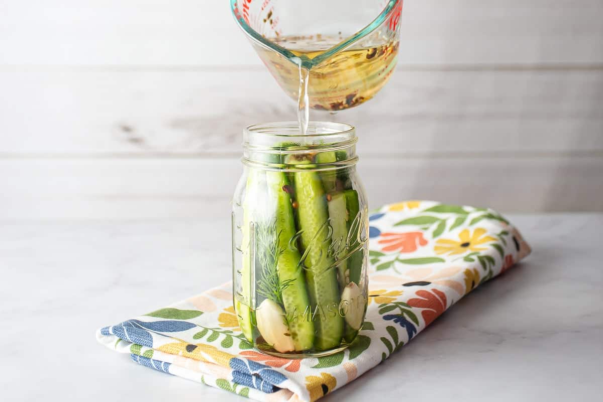 Pouring bring into the jar of pickles.