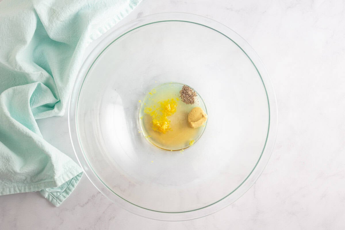 Dressing ingredients for the watermelon feta salad in a large glass bowl before being mixed.