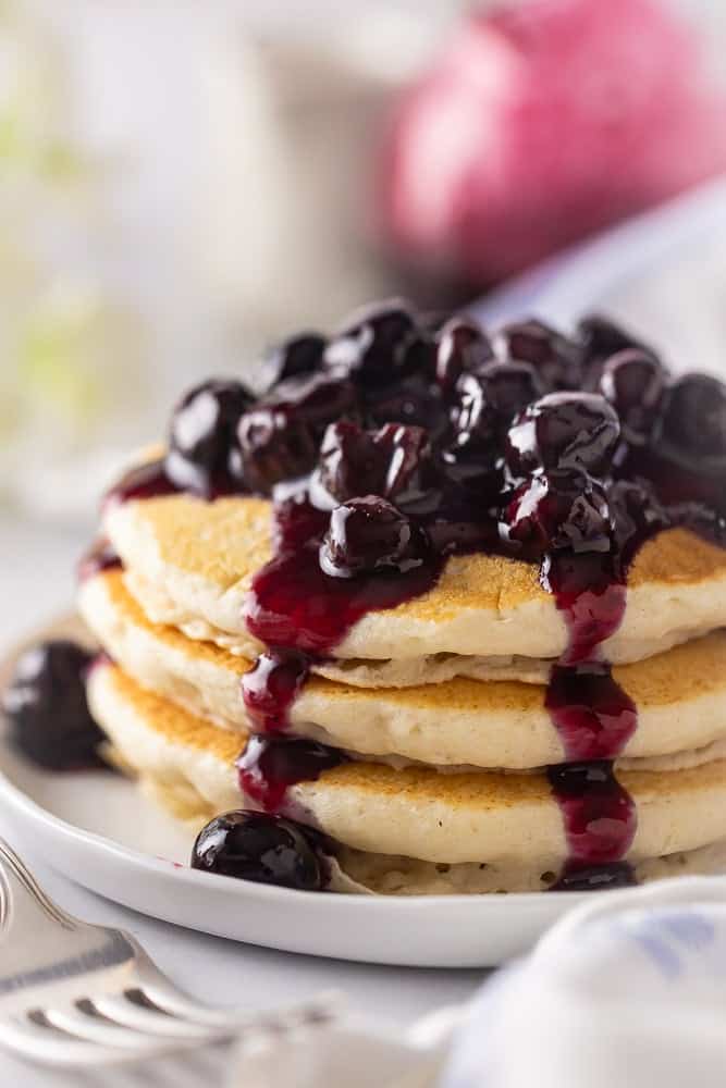 Blueberry syrup on a pile of buttermilk pancakes.