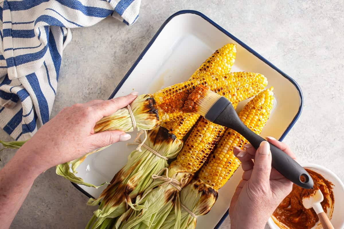Brushing the spread on the corn for elote.