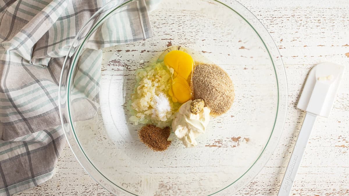 Adding crab cake binder ingredients to a large glass bowl