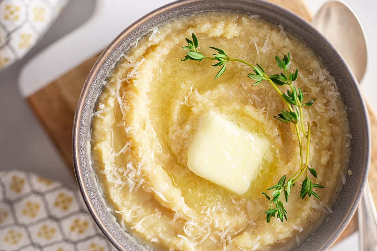 Finished polenta in a serving dish with a pat of partially melted butter on top